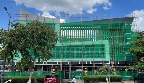Scaffolding and green netting cover the Huione Pay building after its sign was taken down
