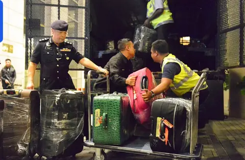 Malaysian police load confiscated suitcases and boxes onto a truck outside apartments linked to Najib Razak at the Pavilion Residences