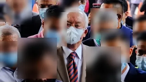 Najib Razak, masked, is escorted into the Kuala Lumpur High Court on the day he was found guilty on all seven SRC International charges