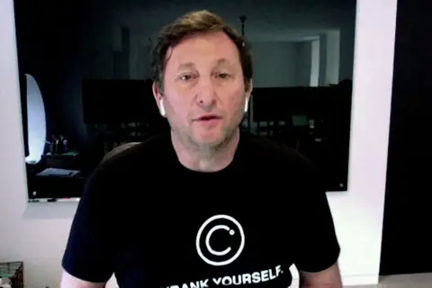 Alex Mashinsky on a video call in a black Celsius T-shirt reading "Unbank Yourself", the slogan that opens the story