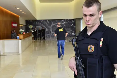 An armed Federal Police officer in the lobby of the Construtora Odebrecht head office during "Operação Acarajé", the 23rd phase of Car Wash