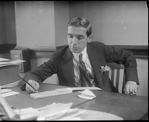 Ponzi at his desk, signing paper, during the last weeks of the scheme