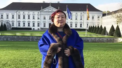 Qian Zhimin, in a fur-trimmed blue coat, poses in front of Bellevue Palace in Berlin during her years of travel on the run